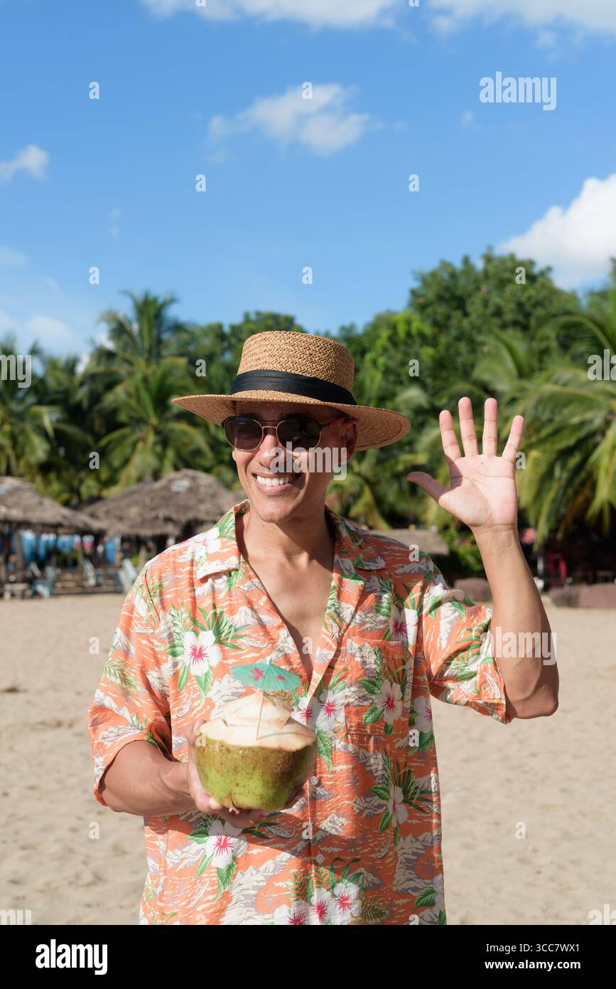 Homme hispanique portant un chapeau Panama et une chemise hawaïenne, habillé dans un style de vacances d'été décontracté. Il pose à la plage, montrant une atmosphère de vacances détendue Banque D'Images Homme hispanique portant un chapeau Panama et une chemise hawaïenne, habillé dans un style de vacances d'été décontracté. Il pose à la plage, montrant une atmosphère de vacances détendue Banque D'Images
