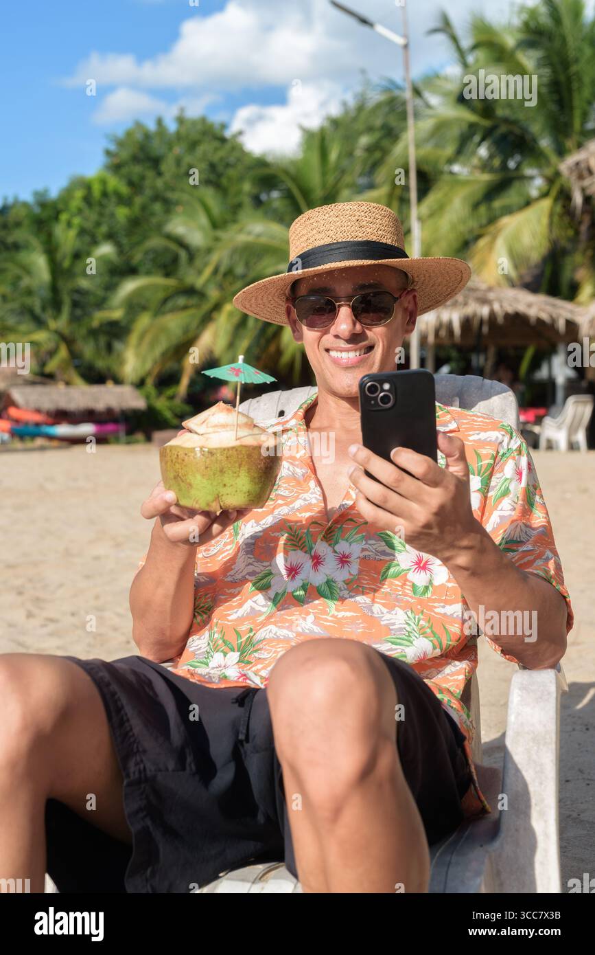 Homme hispanique portant un chapeau Panama et une chemise hawaïenne, habillé dans un style de vacances d'été décontracté. Il pose à la plage, montrant une atmosphère de vacances détendue Banque D'Images Homme hispanique portant un chapeau Panama et une chemise hawaïenne, habillé dans un style de vacances d'été décontracté. Il pose à la plage, montrant une atmosphère de vacances détendue Banque D'Images