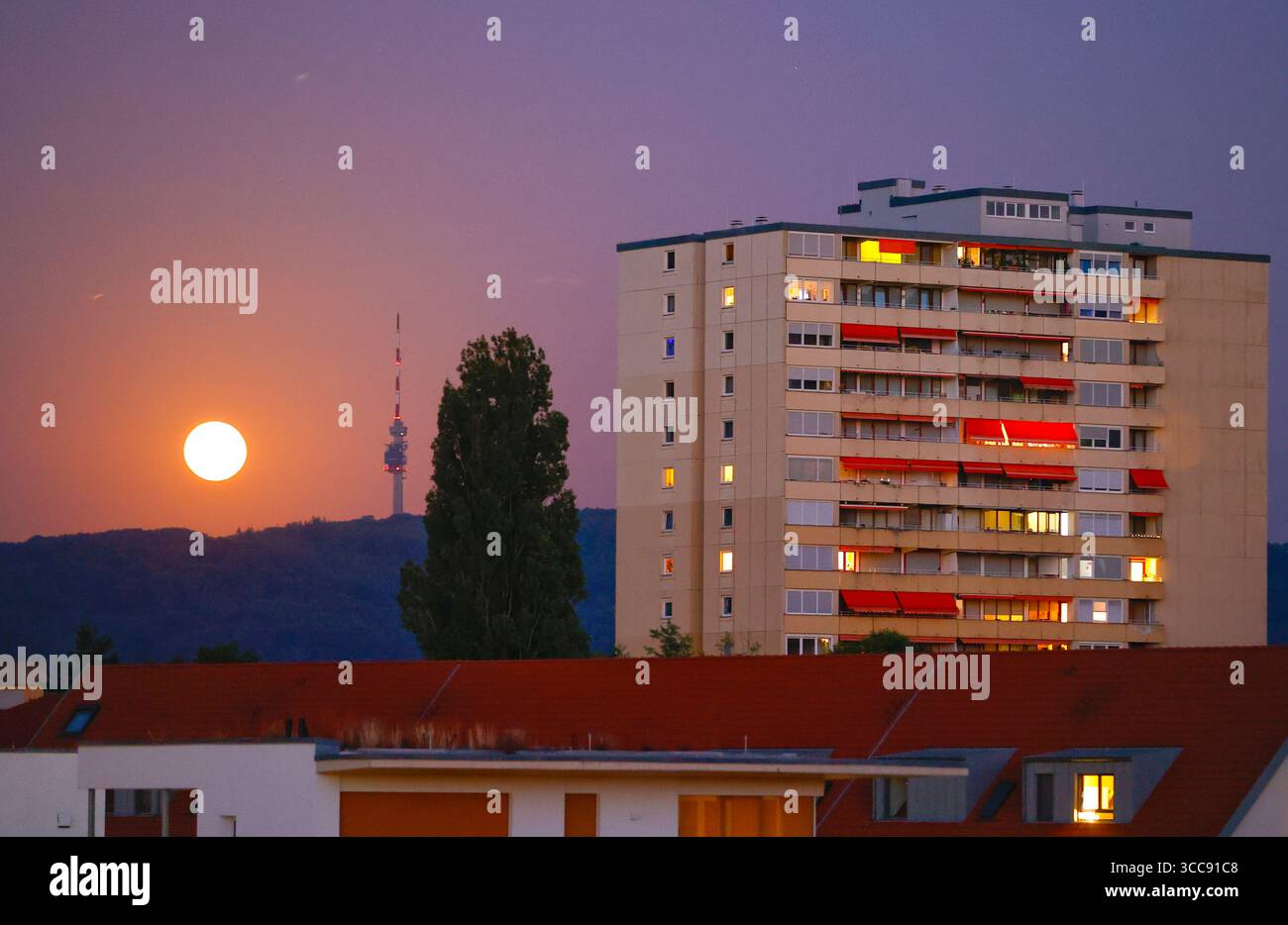 Weil am Rhein, Allemagne - 09 août 2025 : la Lune brille la nuit pendant l'heure bleue à côté d'un gratte-ciel. Mond, Mondschein, Lune, Nachts, Nacht, Banque D'Images
