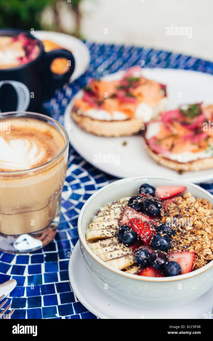 Petit déjeuner bol avec granola, bananes et baies à côté du Latte Banque D'Images