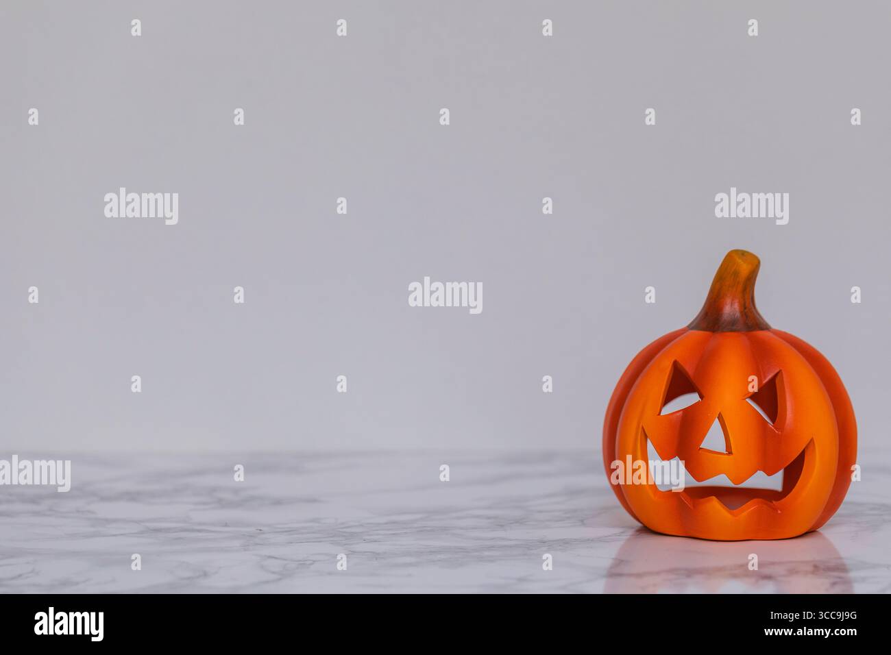 Citrouille jack-o’-lanterne d’Halloween sur surface en marbre avec espace de copie, décoration sculptée effrayante pour les vacances d’automne et la célébration saisonnière Banque D'Images