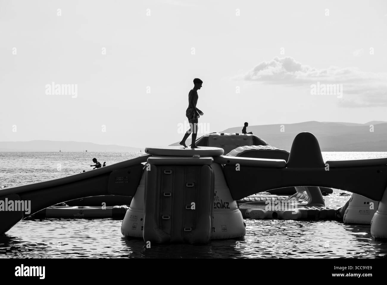 Les gens s'amusent sur le parc aquatique gonflable avec toboggans et obstacles lors d'une journée ensoleillée à Makarska, Croatie le 20 août 2024 Banque D'Images