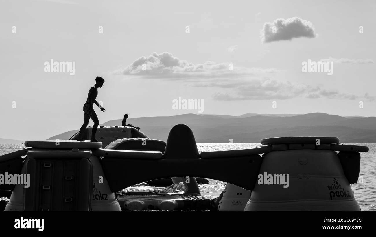 Les gens s'amusent sur le parc aquatique gonflable avec toboggans et obstacles lors d'une journée ensoleillée à Makarska, Croatie le 20 août 2024 Banque D'Images