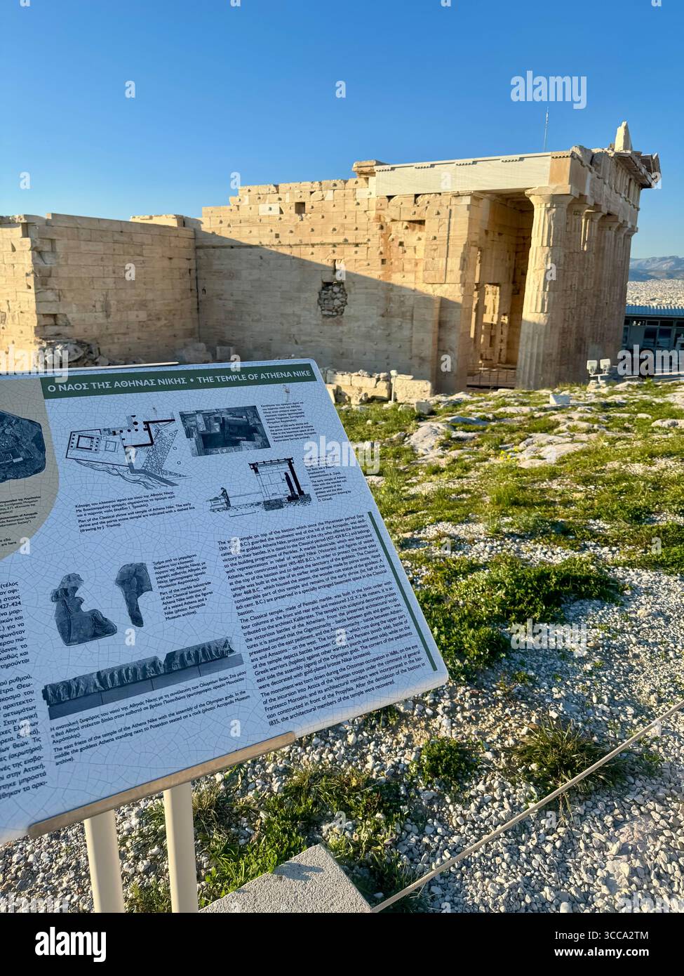 Plaque d'information détaillant le temple d'Athéna sur l'Acropole à Athènes, Grèce, avec pour toile de fond des ruines antiques et un ciel clair. Banque D'Images