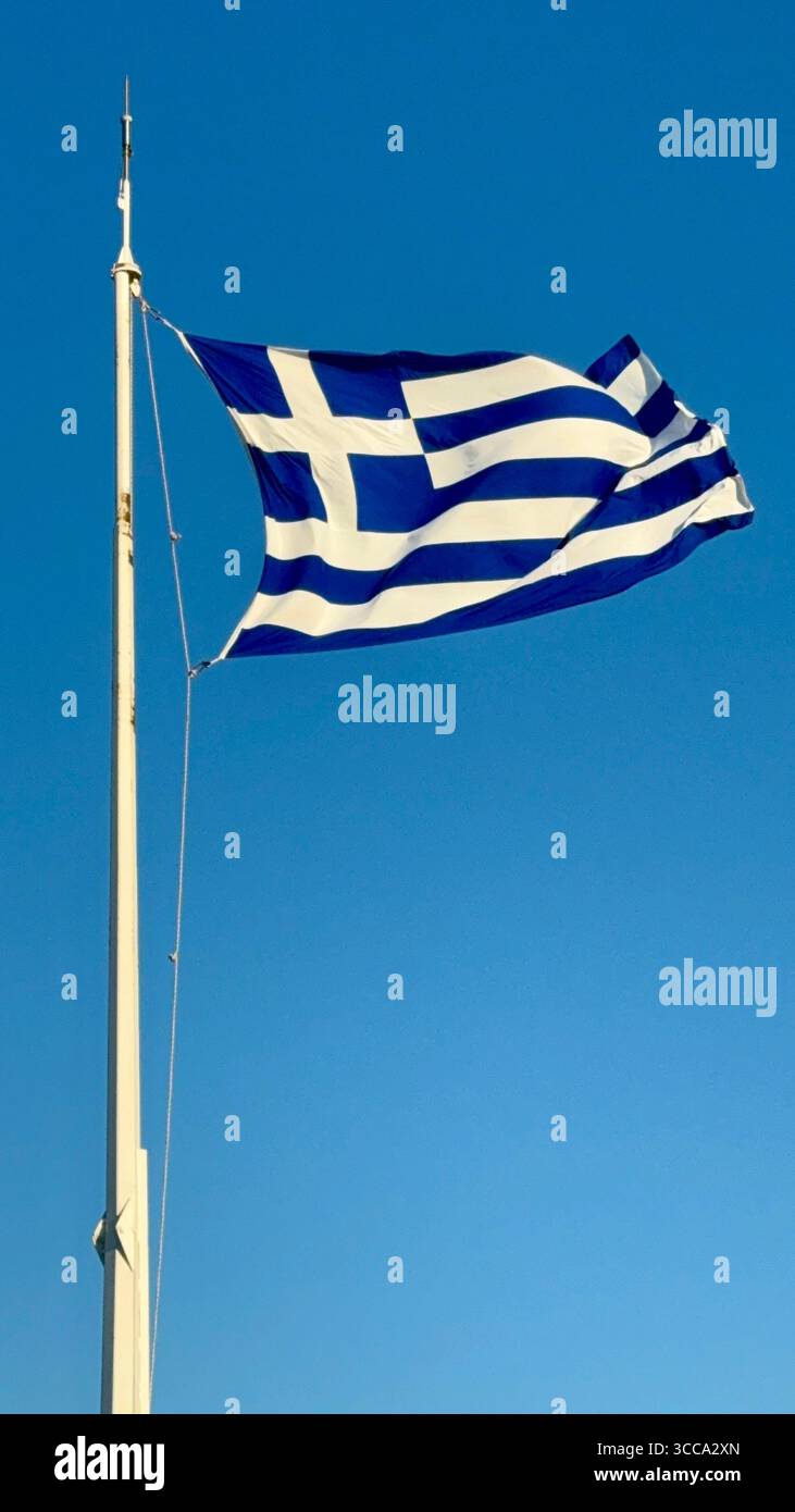 Drapeau grec agitant contre un ciel bleu clair à Athènes, Grèce. - Image de stock capturée avec un smartphone
