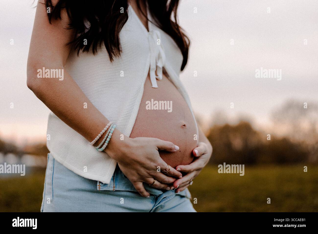 Femme tenant sa bosse de bébé au coucher du soleil dans un parc Banque D'Images