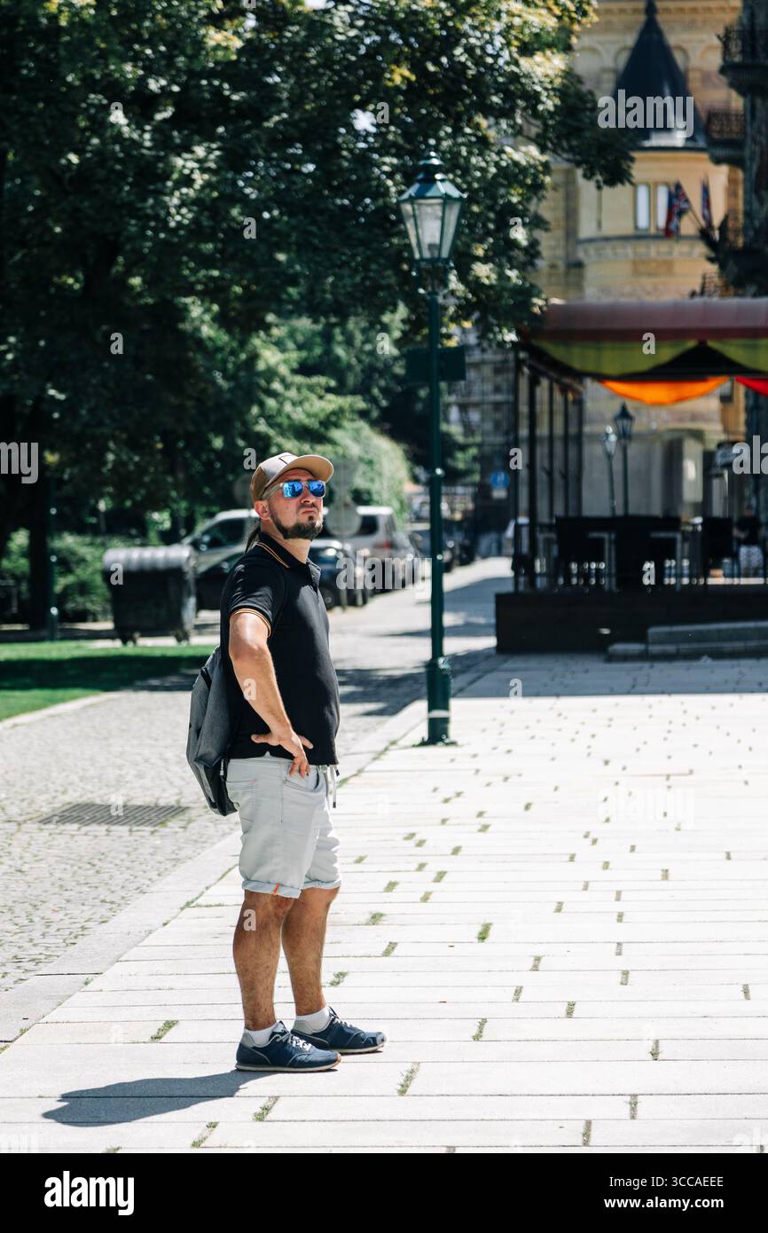 Homme en vêtements décontractés debout sur la rue ensoleillée de la ville Banque D'Images
