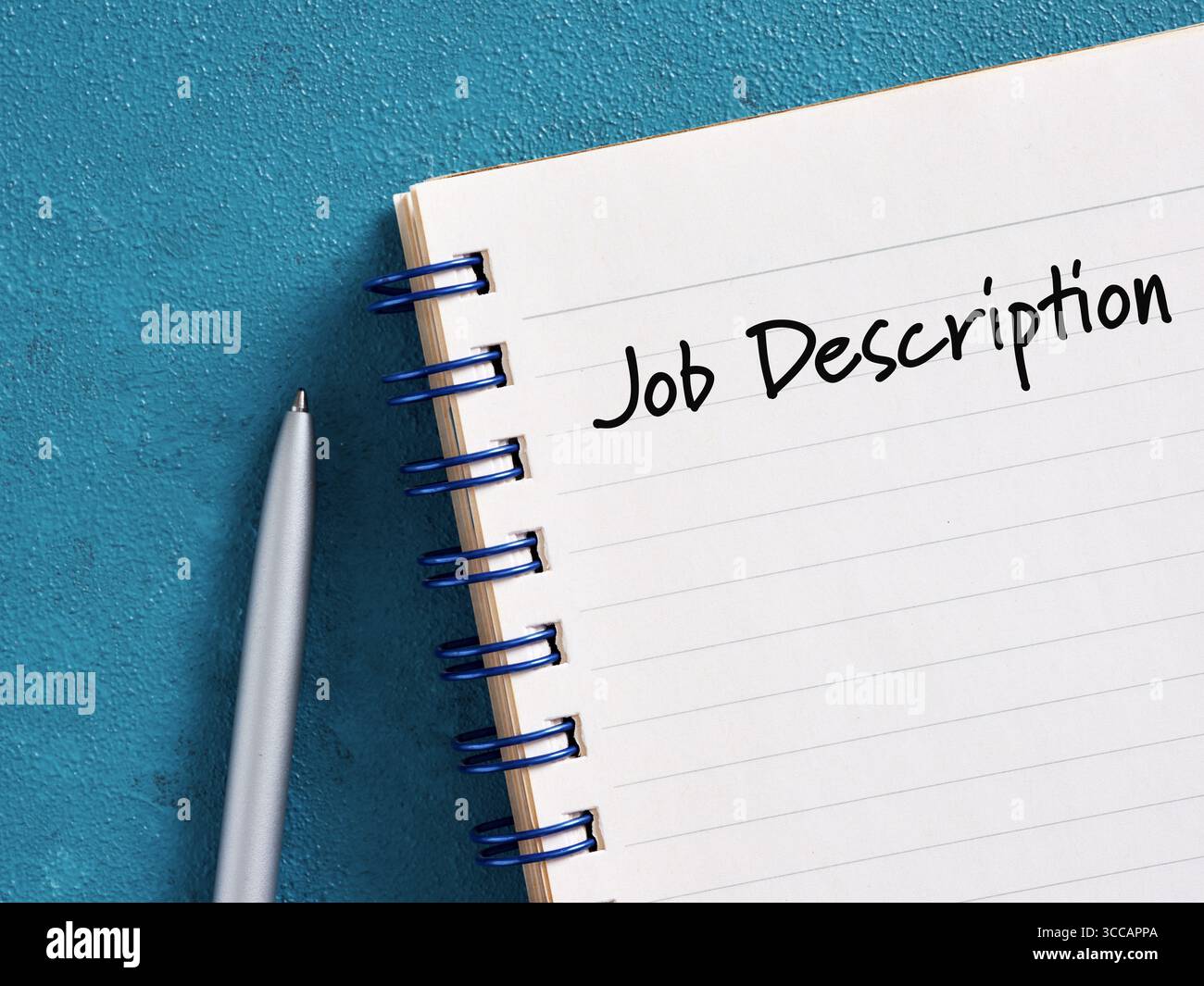 Description de poste écrite sur bloc-notes avec stylo sur bureau bleu, suggérant la planification de carrière et le recrutement Banque D'Images