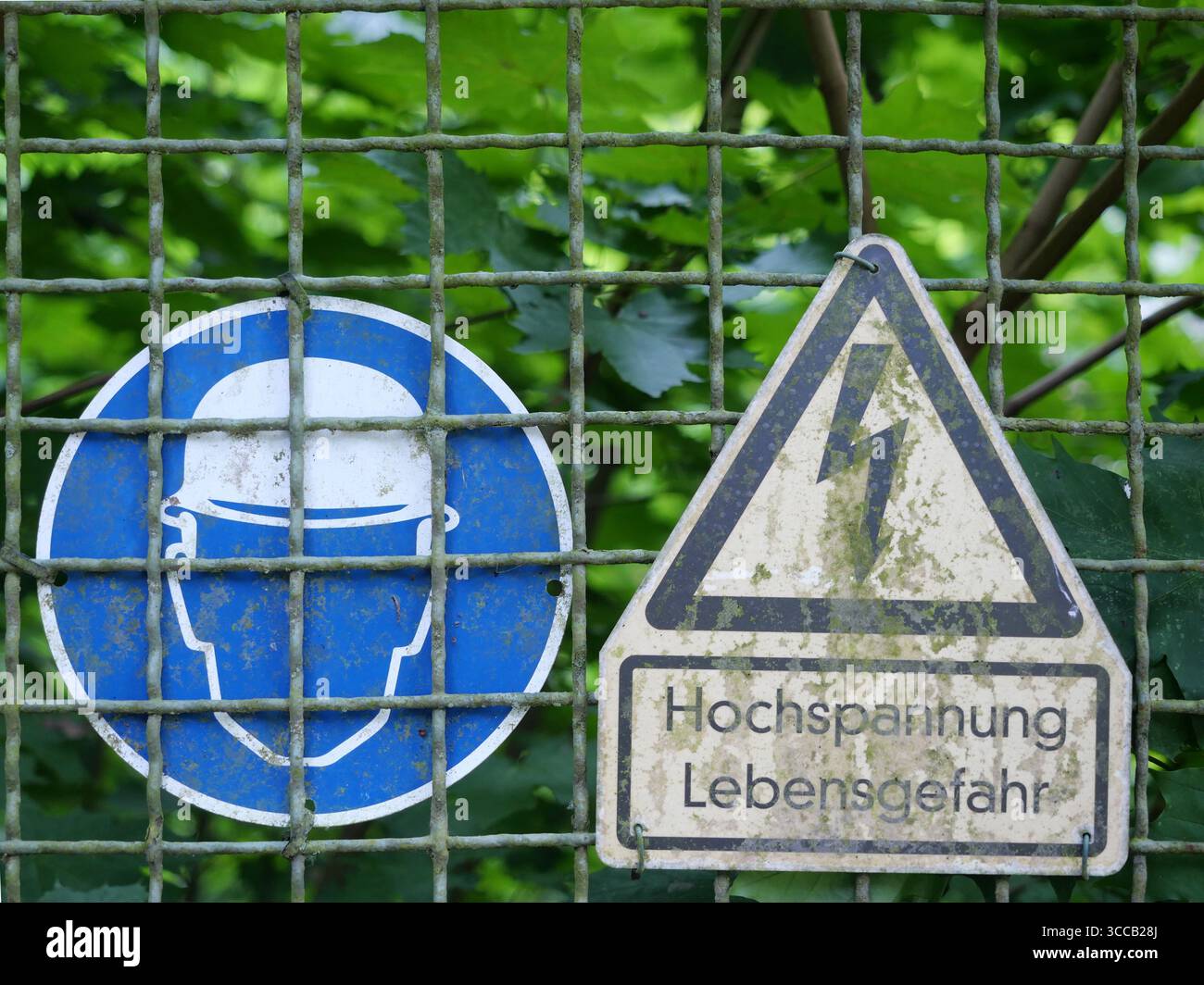 Avertissement de haute tension et signature casque sur la clôture de sécurité. Symboles clairs pour la sécurité et la protection. Copyspace Banque D'Images Avertissement de haute tension et signature casque sur la clôture de sécurité. Symboles clairs pour la sécurité et la protection. Copyspace Banque D'Images