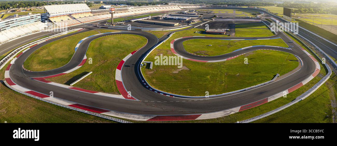 Concord, États-Unis - 28 juillet 2025 : vue aérienne des courbes sinueuses d'asphalte d'une piste de course coupant à travers des champs verdoyants, contrastées par les barrières de sécurité blanches et rouges. Banque D'Images