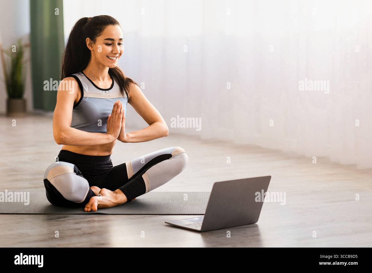 Femme paisible méditant devant un ordinateur portable à la maison Banque D'Images