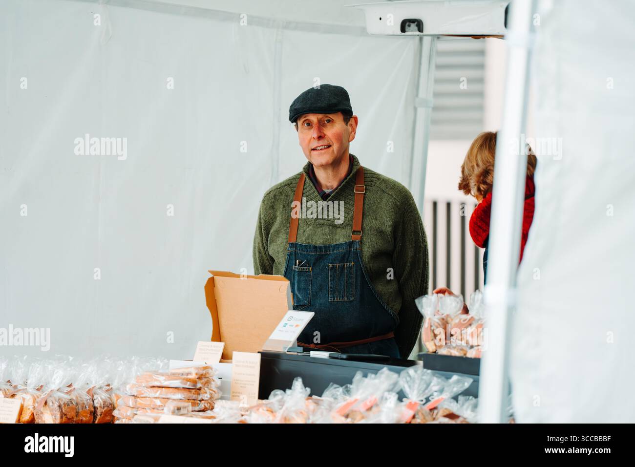 Homme avec une casquette plate servant à un étal de marché, Salamanca Place, Hobart, Tasmanie, Australie Banque D'Images