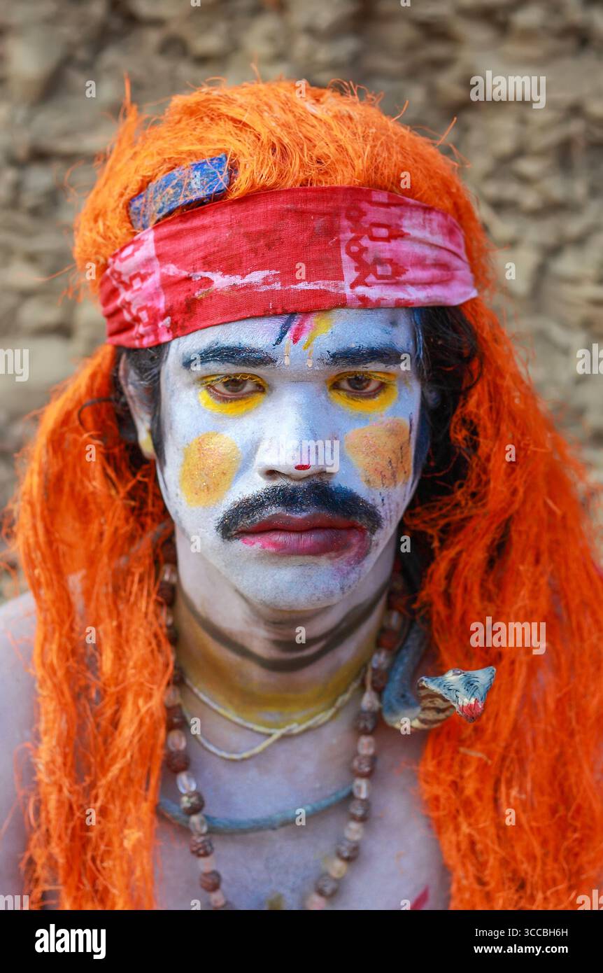 Colline de Chandanath, Bangladesh - 12 mars 2021 : vue d'un homme avec de la peinture pour le visage, orné de cheveux orange éclatants et de perles, sur fond neutre. Banque D'Images