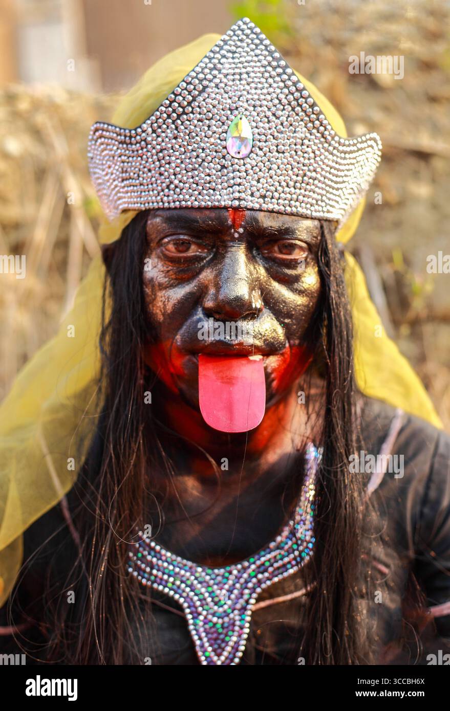 Chandanath Hill, Bangladesh - 12 mars 2021 : vue d'une personne ornée d'un maquillage sombre, d'une couronne d'argent et d'un collier saisissant, la langue étendue, incarnant une personnalité culturelle ou théâtrale. Banque D'Images