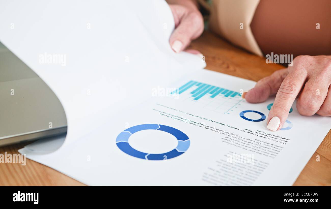 Femme senior analysant les données commerciales et les graphiques sur les documents imprimés Banque D'Images
