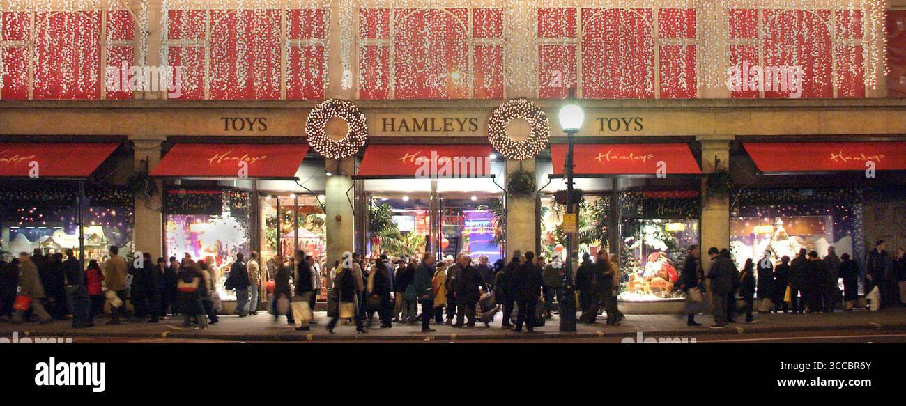 Hamleys Toys le célèbre magasin de shopping vu à l'extérieur 2004 Archival nuit vue nocturne de la boutique Regent Street dans une scène de lumières de Noël des années 2000 avec une élévation décorée au-dessus d'un trottoir piétonnier très fréquenté avec des acheteurs se rassemblant autour de grandes fenêtres affichant des marchandises pour enfants à vendre ciblant la saison d'achat de Noël présent à Regent Street West End Londres Angleterre Royaume-Uni Banque D'Images
