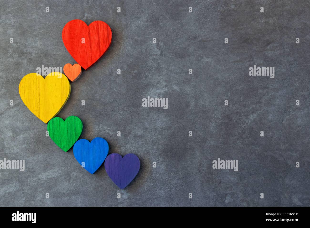 Rainbow couleurs coeurs en bois sur le fond noir de pierre. Drapeau LGBT. Banque D'Images