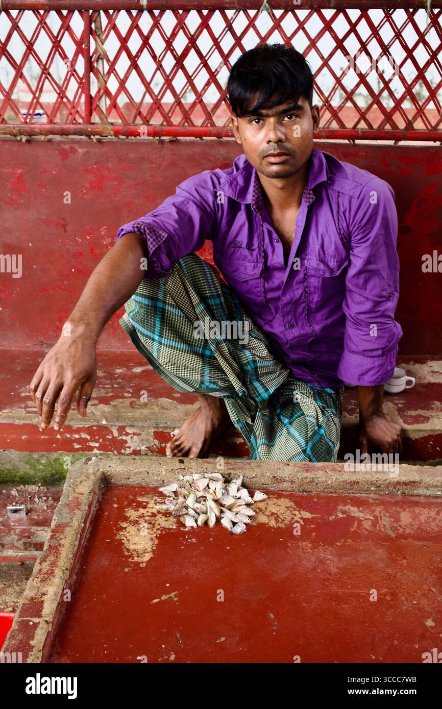 Jeune homme vendant de petits poissons aux visiteurs pour nourrir des tortues dans le complexe Hazrat Shah Jalal mazar à Sylhet, Bangladesh. Banque D'Images