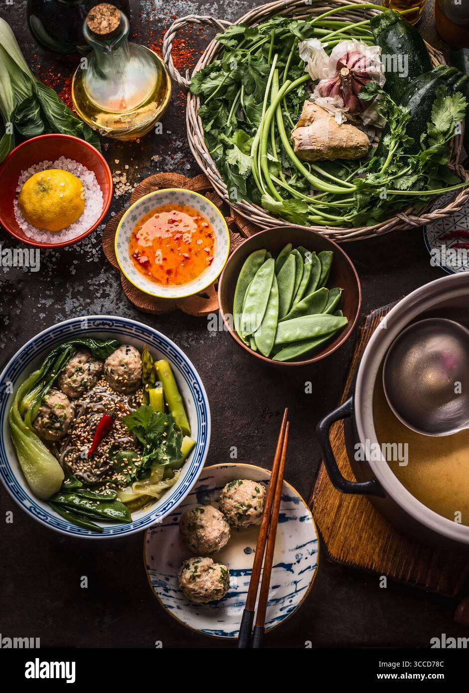 La cuisine asiatique. Soupe de nouilles avec des légumes savoureux et les boulettes de viande dans un bol garni de graines de sésame et le piment sur table de cuisine rustique avec des ingrédients : Herb Banque D'Images