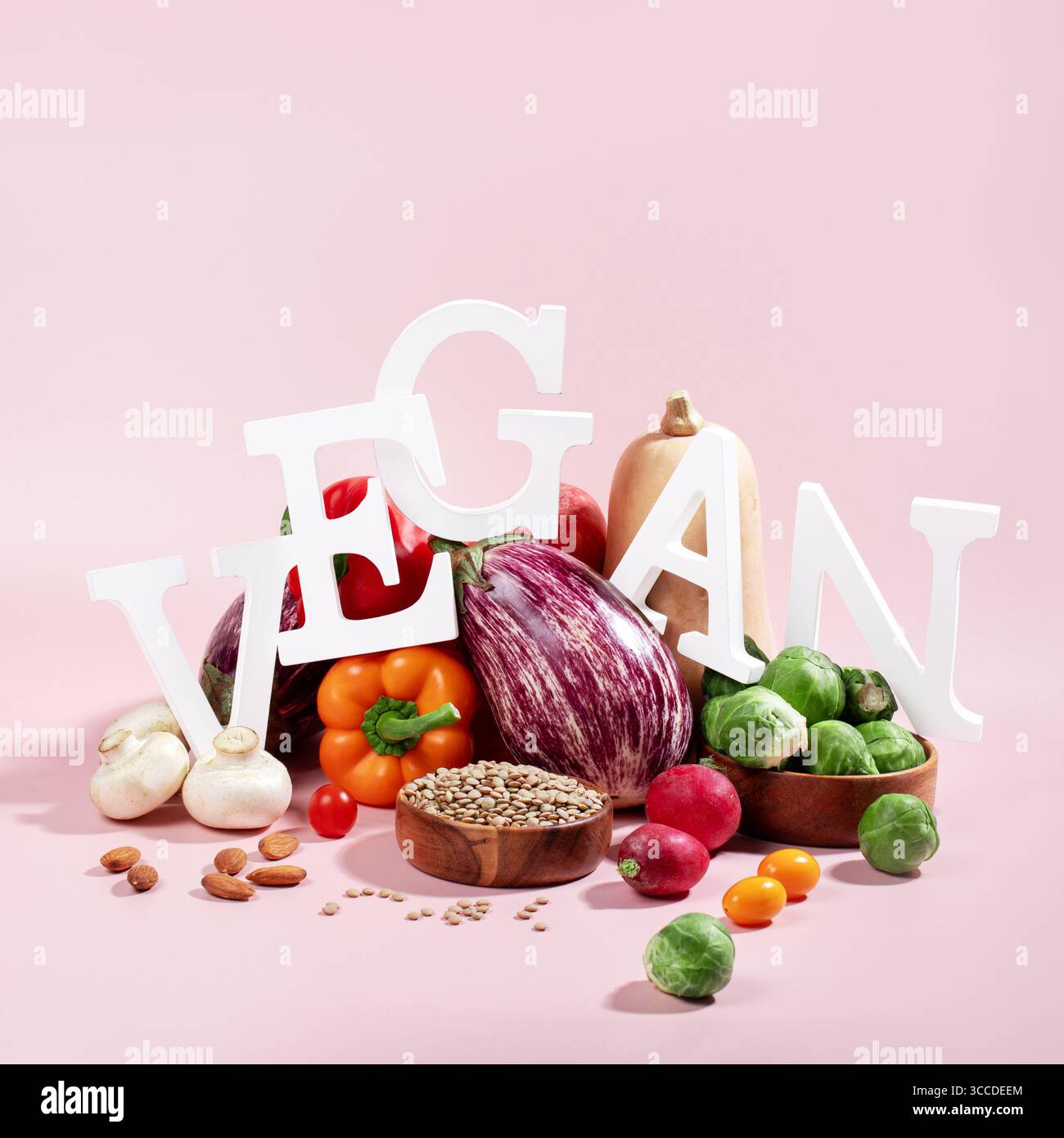 Le mot VEGAN en grandes lettres sur la table rose, entouré de fruits frais, légumes et un bol de lentilles, régime végétalien nature morte Banque D'Images
