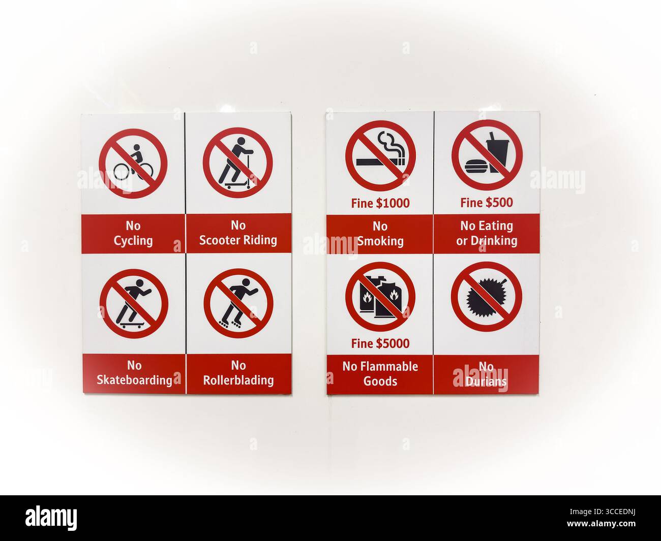 Panneau avec de multiples panneaux d'interdiction, y compris l'interdiction de faire du vélo, l'interdiction de fumer, l'interdiction de durians, et des amendes pour violations, affiché sur un mur blanc singapour Banque D'Images