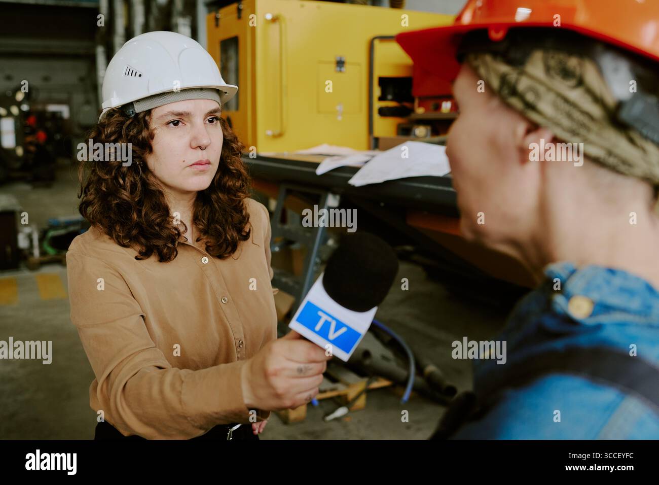 Femme jeune adulte caucasienne interviewant une femme d'âge moyen en milieu industriel Banque D'Images