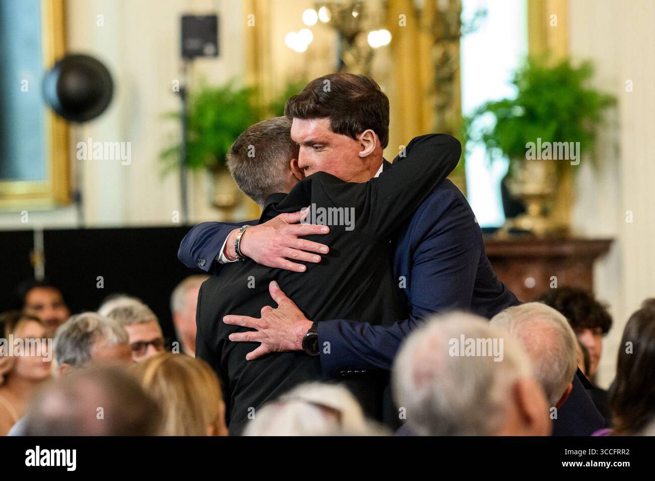 Un récipiendaire de Purple Heart embrasse un autre participant lors d'une cérémonie à la Maison Blanche honorant les membres du service militaire lors de la Journée nationale Purple Heart. Washington, DC. 7 août 2025. Image reproduite avec l'aimable autorisation de la Maison Blanche. Banque D'Images