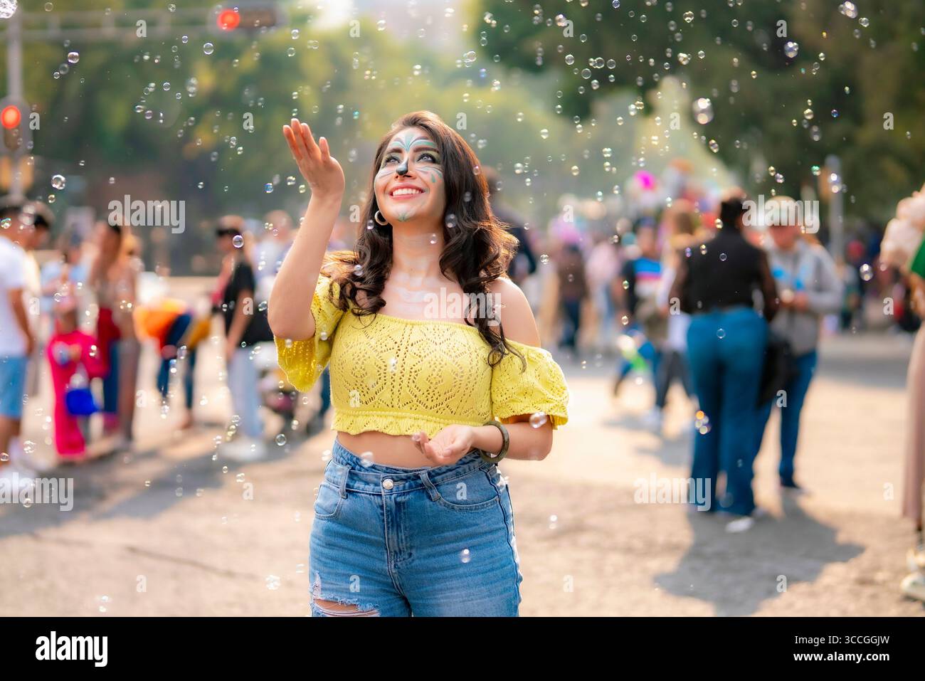 Jeune femme heureuse de Latina avec le maquillage artistique catrina joue avec des bulles de savon sur Reforma pendant le défilé Dia de Muertos à Mexico, portant un YE Banque D'Images