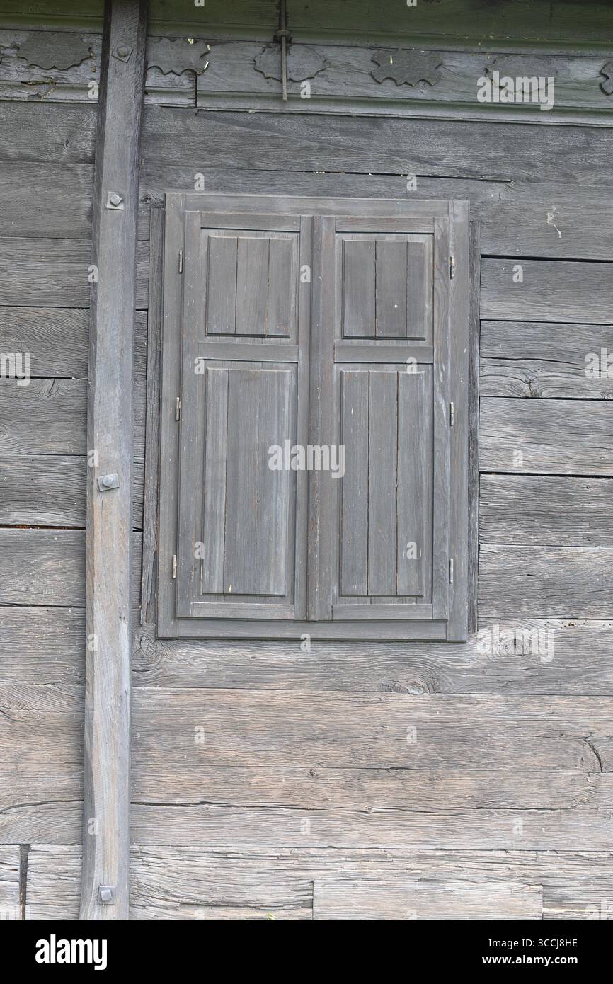 Mur en bois rustique présentant une texture vibrante et des volets fermés, soulignant la charmante simplicité et l'élégance de l'artisanat en bois. Banque D'Images
