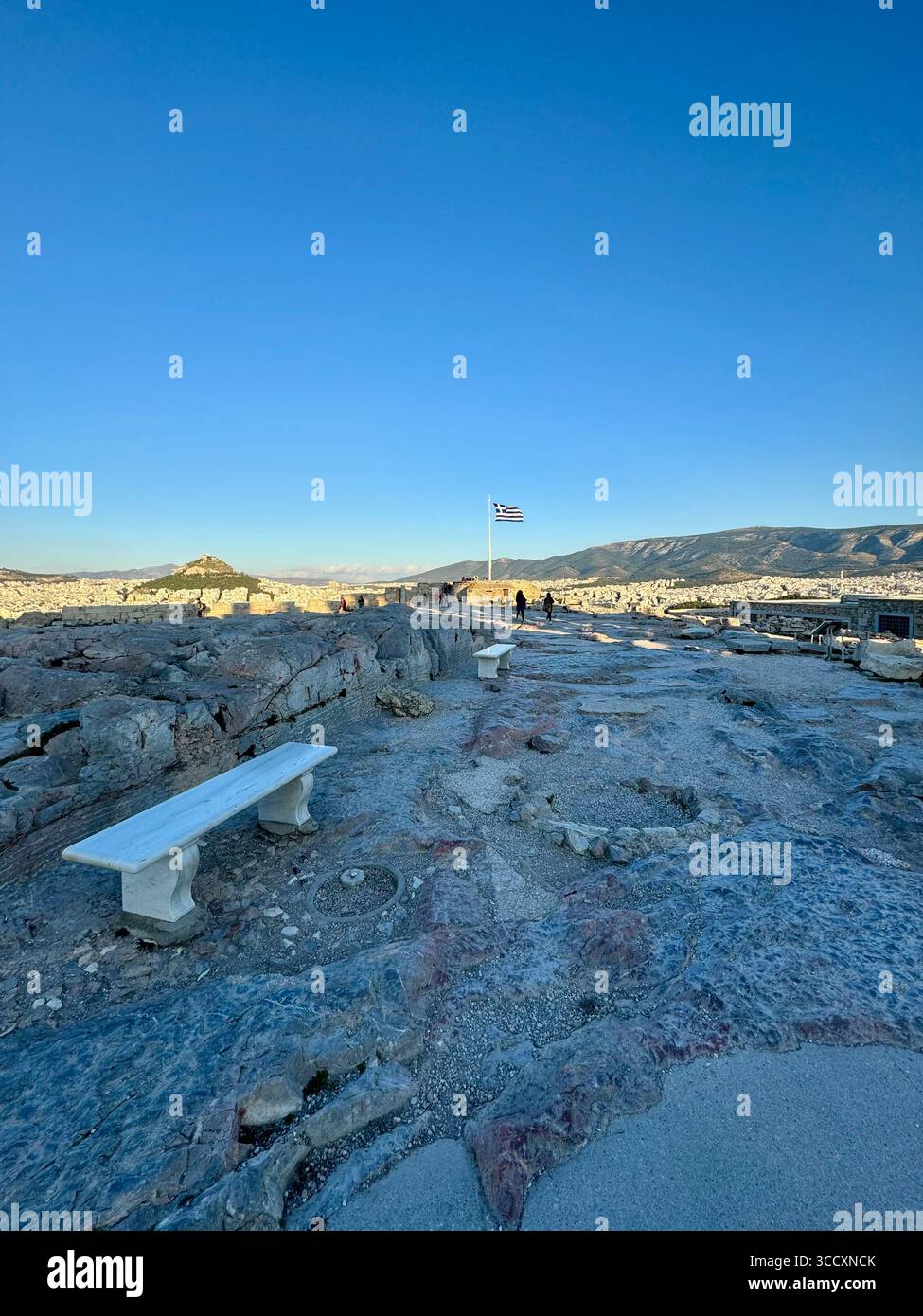 Le drapeau grec flotte fièrement au monument du drapeau au sommet de l'Acropole à Athènes, en Grèce, offrant une vue panoramique sur la ville. Banque D'Images