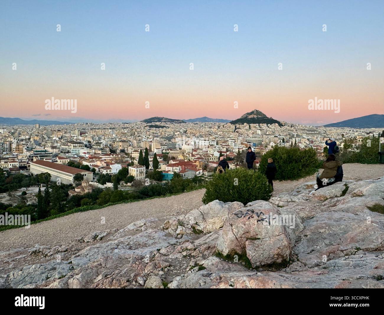 Couleurs de coucher de soleil peignant le ciel au-dessus d'Athènes, vu de la colline d'Aréopage avec l'Acropole et la colline de Lycabette en arrière-plan. - Image de stock capturée avec un smartphone