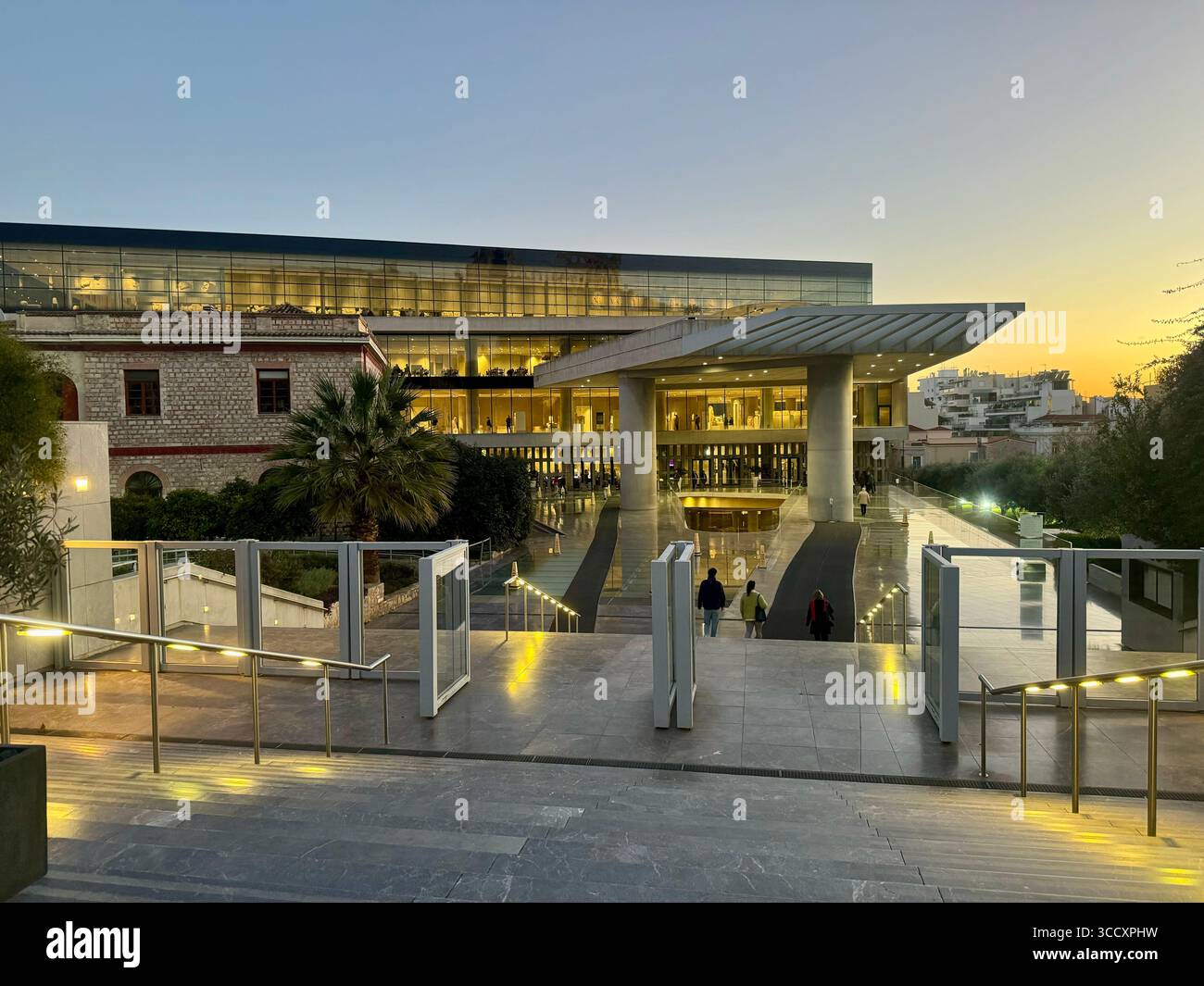 Entrée au Musée de l'Acropole à Athènes, Grèce, illuminée au crépuscule avec les visiteurs entrant dans le bâtiment architectural moderne. Banque D'Images