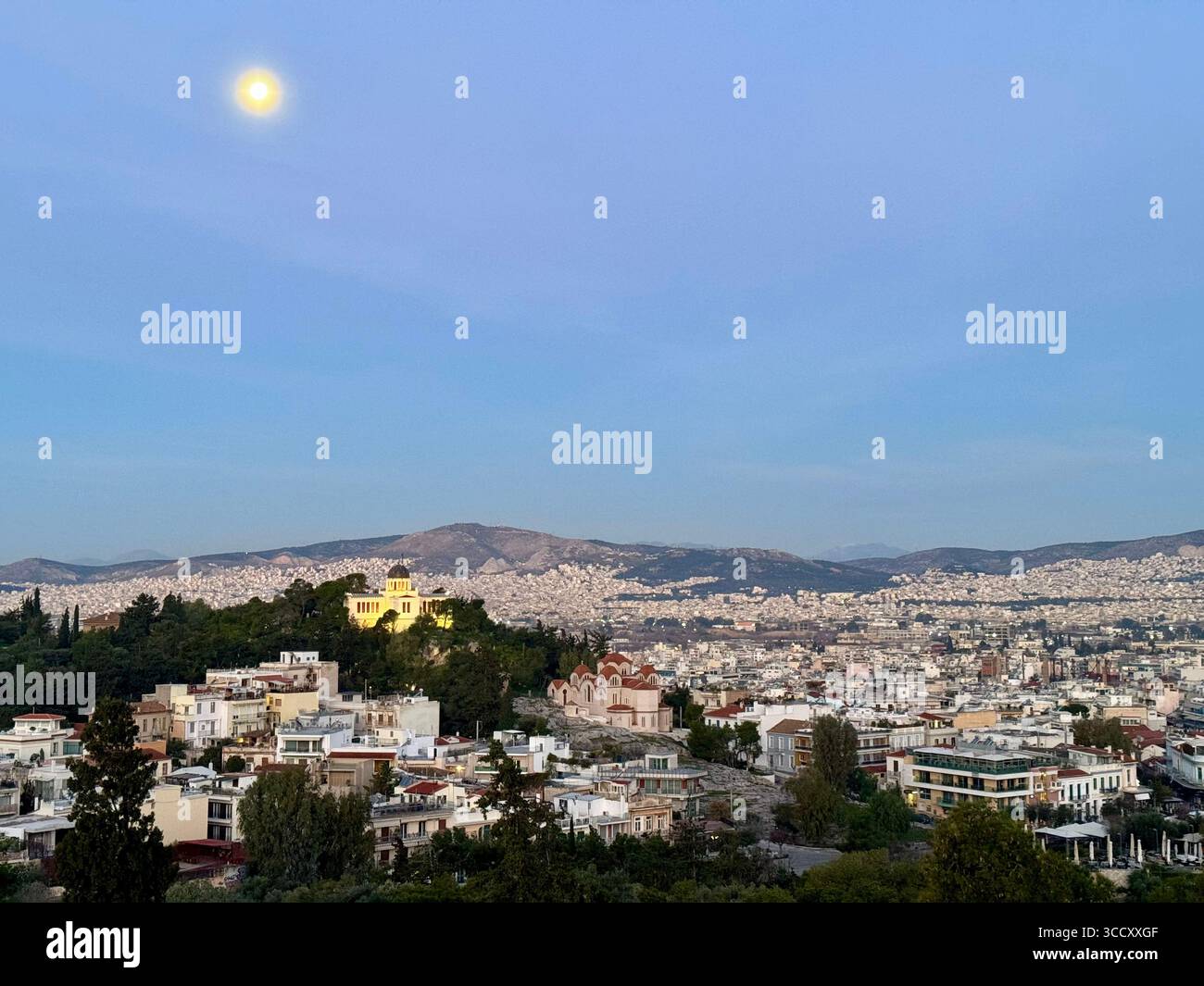 Vue du lever du soleil depuis la colline d'Areopagus avec le paysage urbain d'Athènes, mettant en valeur le bâtiment jaune et la montagne lointaine. - Image de stock capturée avec un smartphone