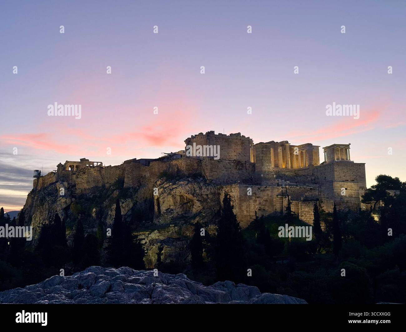 Lever de soleil sur la colline d'Areopagus avec la lumière chaude du matin illuminant l'Acropole et le paysage urbain d'Athènes. Banque D'Images