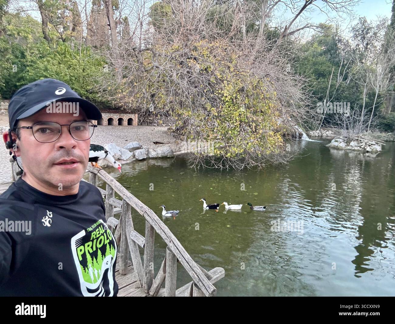 Homme jogging par un étang tranquille dans le jardin national d'Athènes, entouré par la nature et les canards. Banque D'Images