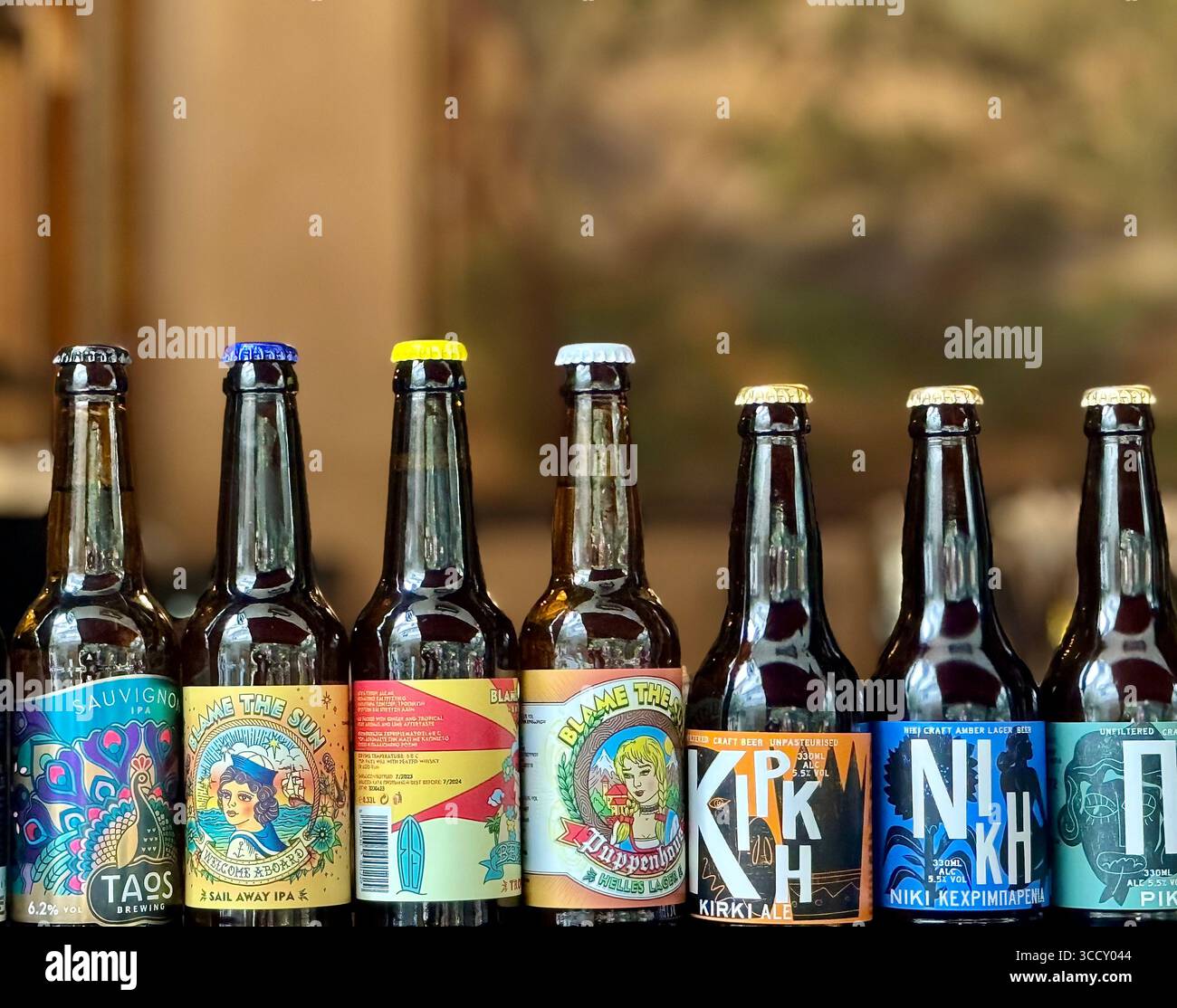 Assortiment de bouteilles de bière grecques avec étiquettes colorées alignées. Banque D'Images