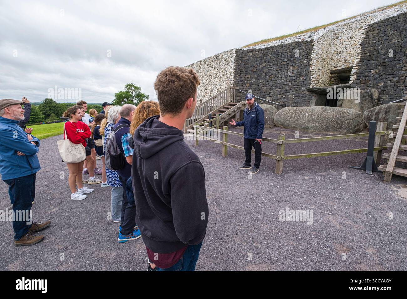 Groupe de touristes écoutant la guilde locale parler de Newgrange tumulus, Brú na Bóinne, Stalleen, County Meath, Irlande Banque D'Images