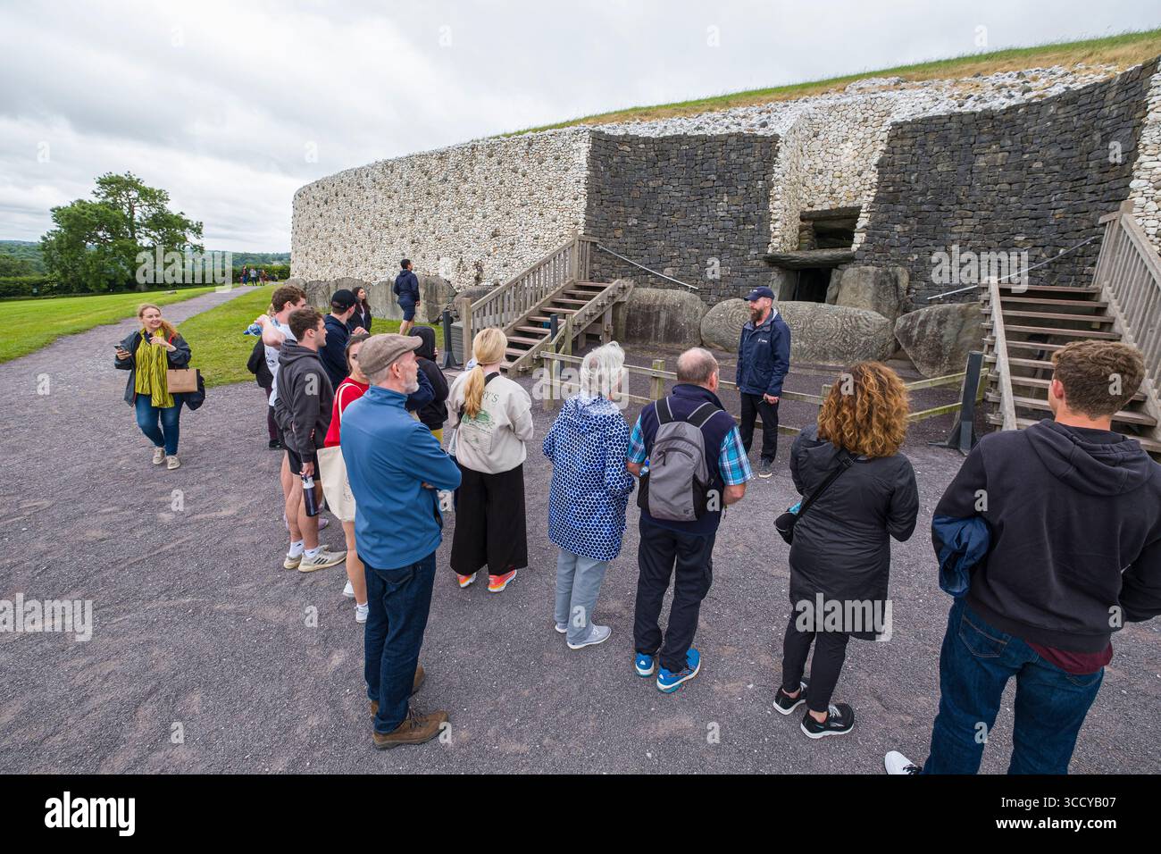 Groupe de touristes écoutant la guilde locale parler de Newgrange tumulus, Brú na Bóinne, Stalleen, County Meath, Irlande Banque D'Images
