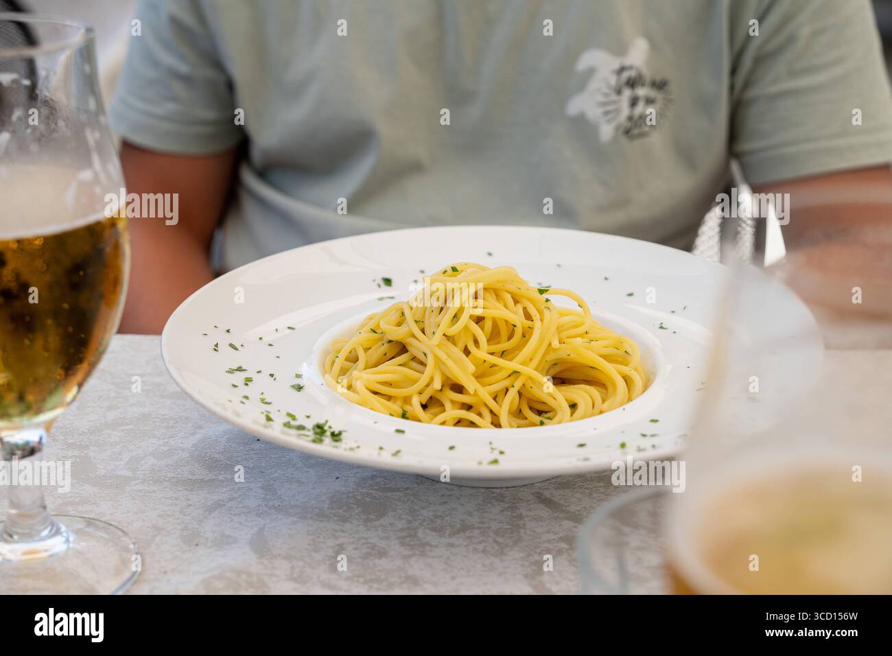 Limone, Lac de Garde, Italie 7 août 2025 : spaghetti aglio e olio pâtes classiques avec ail, huile d'olive et peperoncino dans un restaurant avec un invité et de la bière. *** Spaghetti aglio e olio klassische Pasta mit Knoblauch, Olivenöl und Peperoncino im Restaurant mit Gast und Bier. Banque D'Images