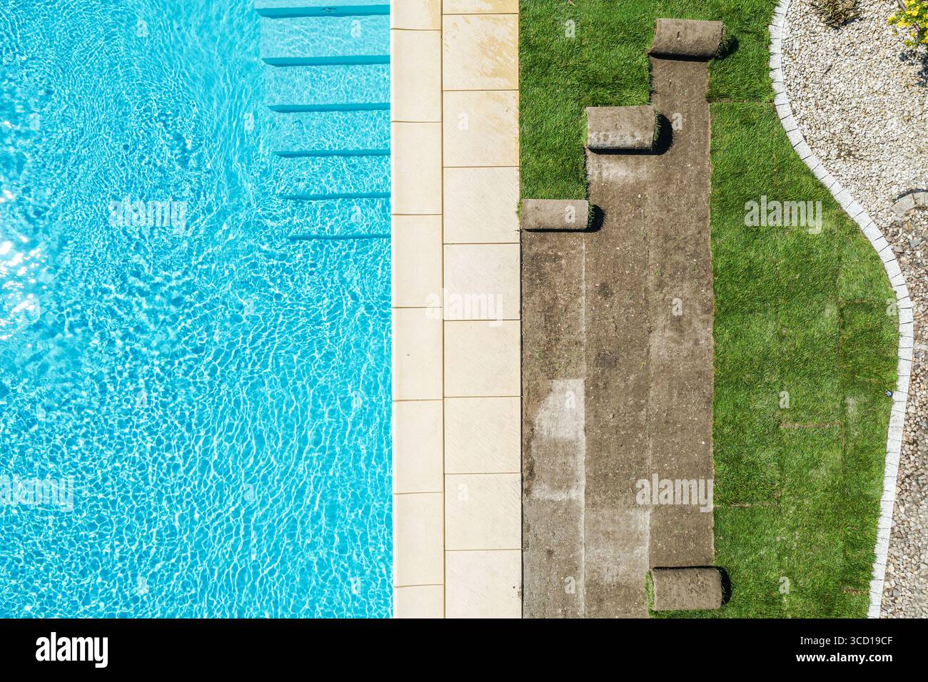 Une piscine lumineuse et accueillante dispose d'eau bleue claire, de carreaux de pierre et de taches herbeuses avec des espaces lounge, parfaits pour se détendre au soleil Banque D'Images
