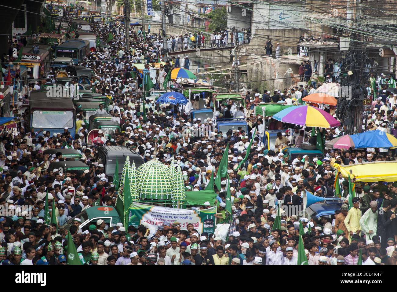 Chattogram, Bangladesh - 08 octobre 2022 : vue d'une foule dense avec des drapeaux verts, des banderoles et des parapluies dans les rues, une mer d'humanité sous l'horizon urbain. Banque D'Images