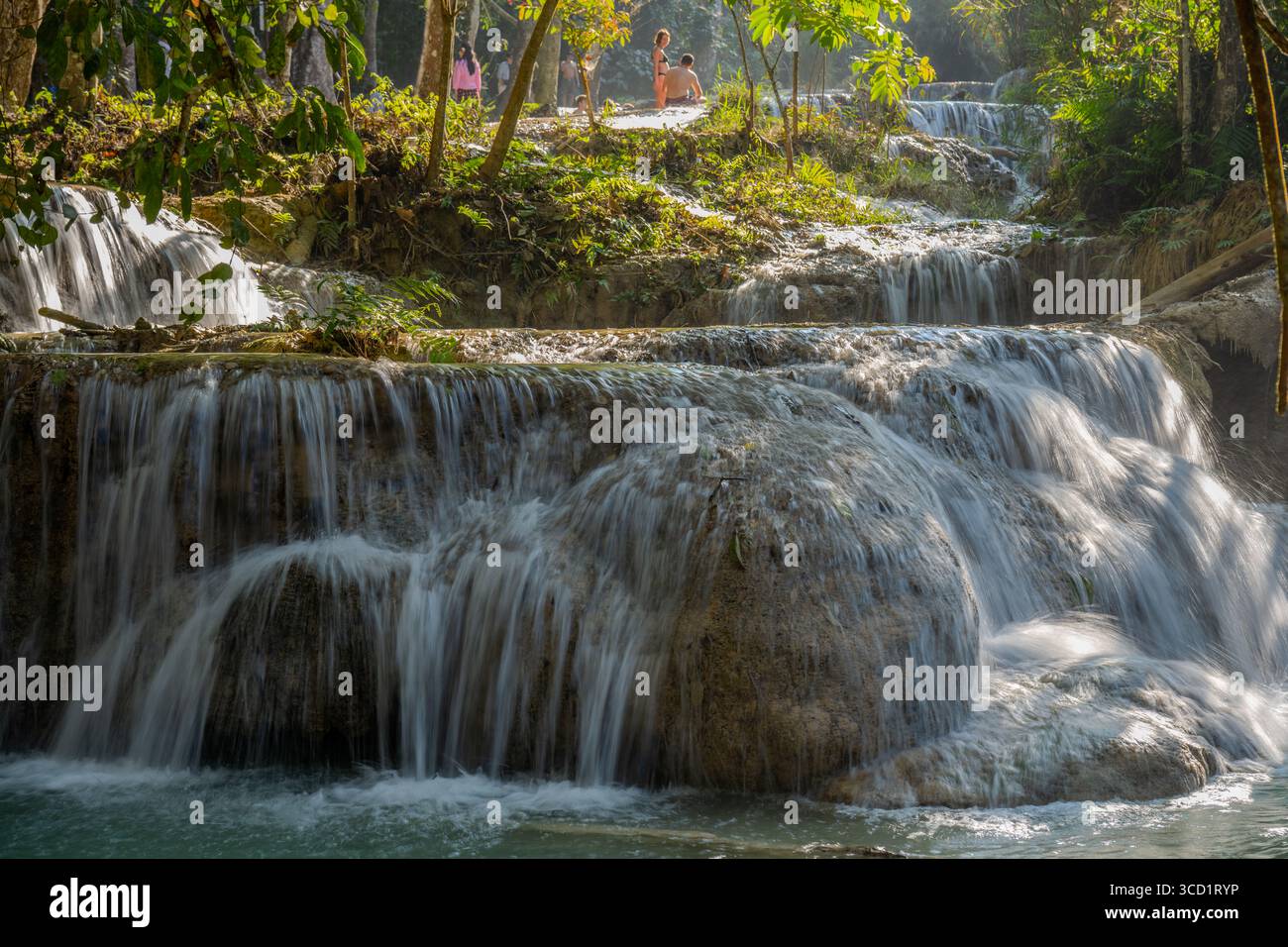 Visiteurs appréciant les cascades de Kuang si à plusieurs niveaux qui coulent à travers la jungle tropicale près de Luang Prabang, Laos Banque D'Images