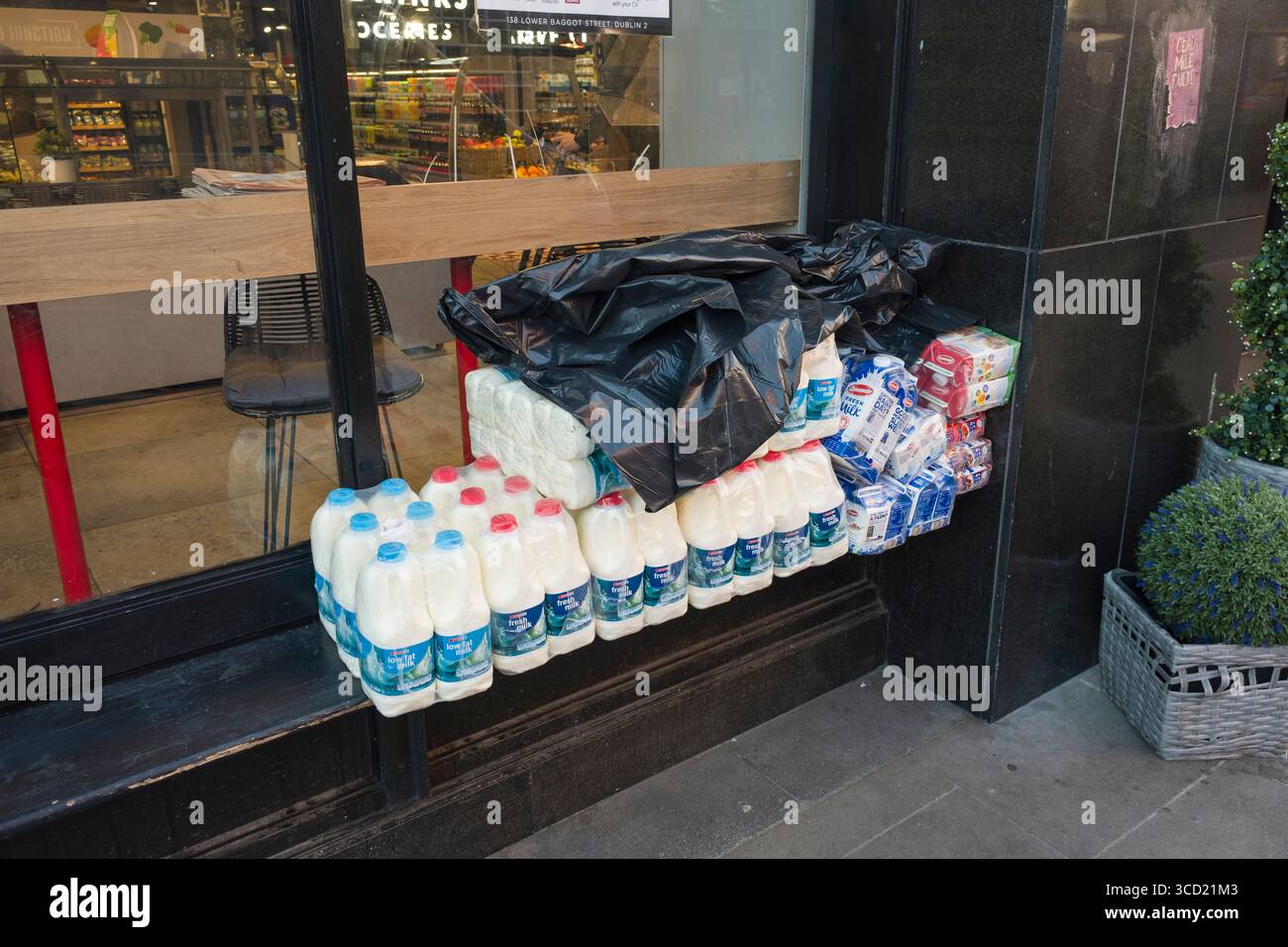 Contenants de 2 litres de lait frais emballés en plastique sur le banc à l'extérieur de l'épicerie SPAR Gourmet, Lower Baggot Street, Southside, Dublin, Irlande Banque D'Images