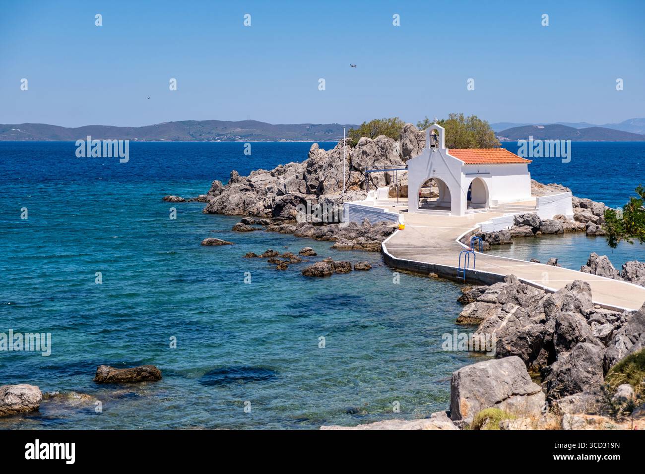 Chios, petite église d'Agios Isidoros, Grèce. Chapelle d'architecture traditionnelle avec toit de tuiles rouges et clocher sur les rochers, journée d'été ensoleillée Banque D'Images