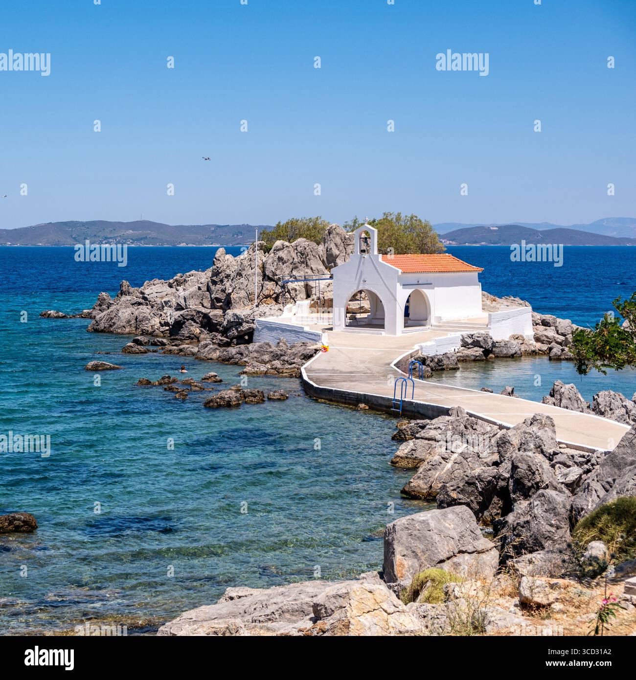 Chios, petite église d'Agios Isidoros, Grèce. Chapelle d'architecture traditionnelle avec toit de tuiles rouges et clocher sur les rochers, journée d'été ensoleillée Banque D'Images