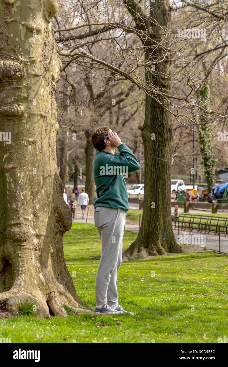 Vue en bas angle d'une femme observant l'éclipse solaire d'avril 2024 à Central Park, Manhattan, New York, États-Unis, capturant la vie urbaine et extérieure Banque D'Images