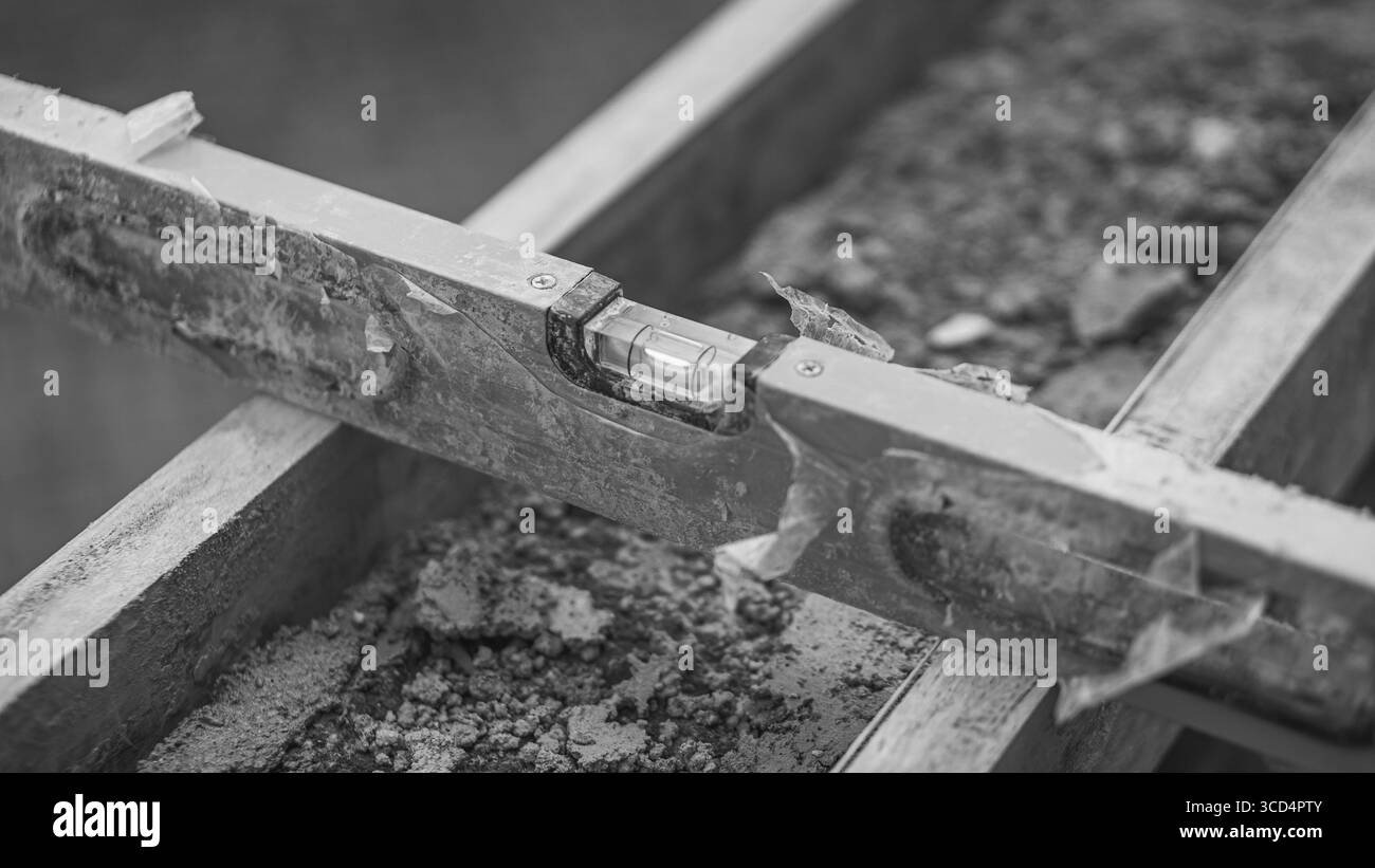 Un niveau à bulle repose sur du béton pour assurer la planéité de la surface, une étape essentielle pour maintenir la précision et la qualité des travaux de construction Banque D'Images