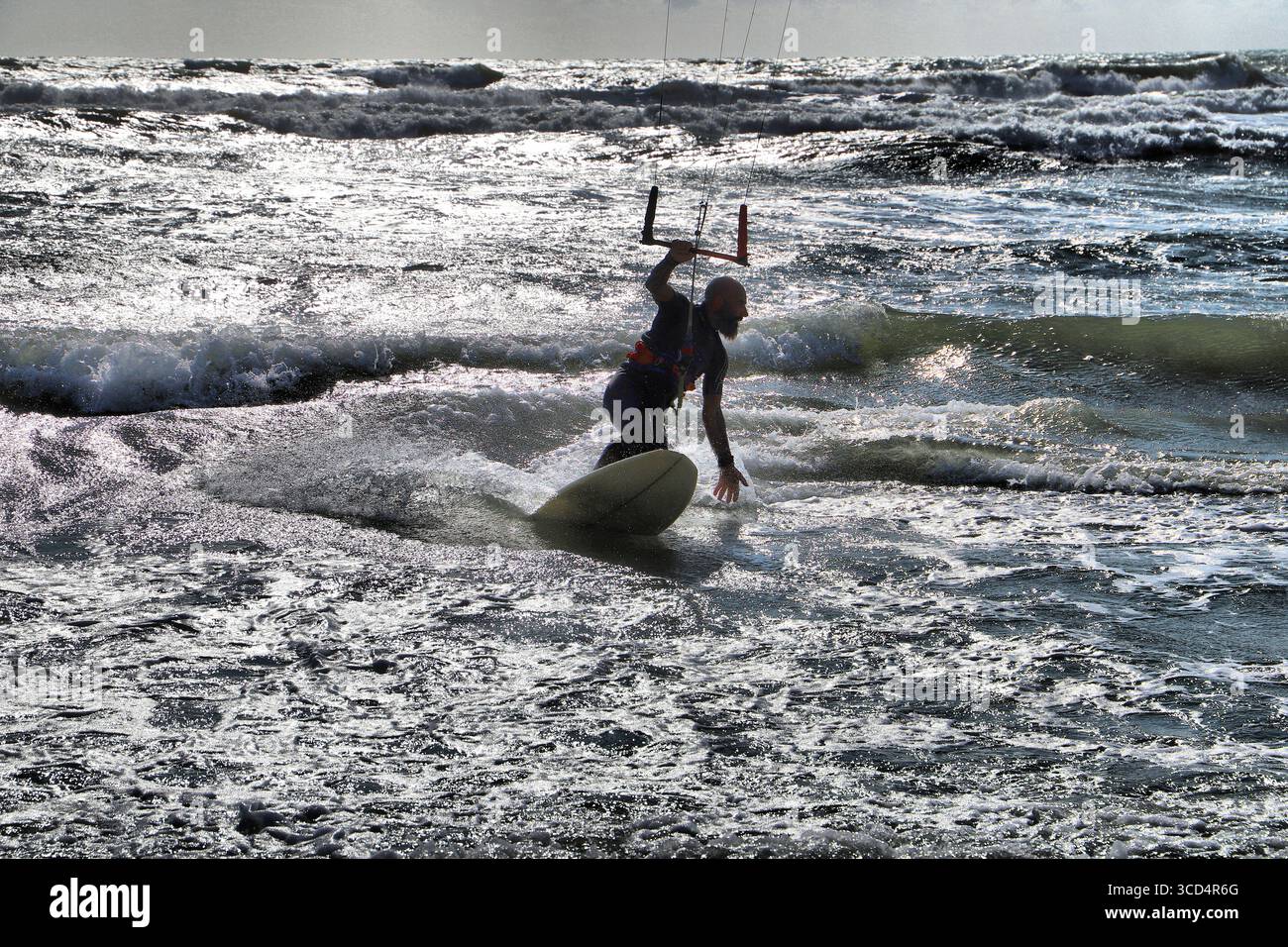 Un kitesurfer glisse dynamiquement sur les vagues de la mer tout en utilisant le vent dans la voile Banque D'Images