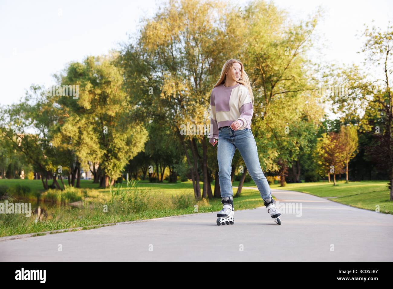 Heureuse jeune femme patin à roulettes dans le parc Banque D'Images
