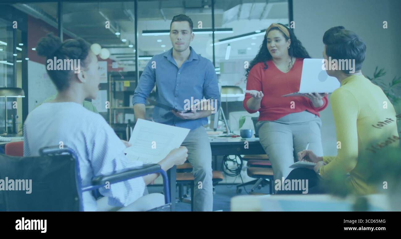 Collaboration professionnels examinant des documents au bureau avec un utilisateur de fauteuil roulant, ordinateur portable, tablette Banque D'Images